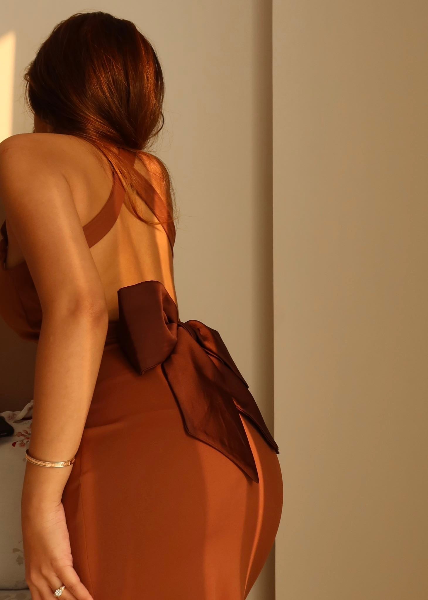 Model walking in rust brown backless dress showing fluid fit and elegant drape